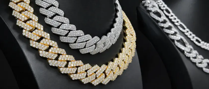 Assorted 316L stainless steel Cuban link chains in 3mm to 14mm widths with 18K gold PVD plating displayed on a jeweler's workbench