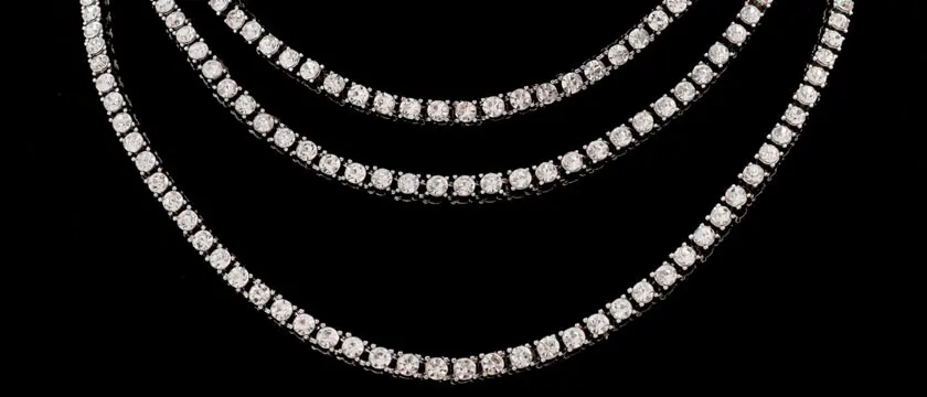 Cubic zirconia tennis necklaces in brass and 925 sterling silver settings with 2mm to 5mm hand-set stones arranged beside a stone grading tray
