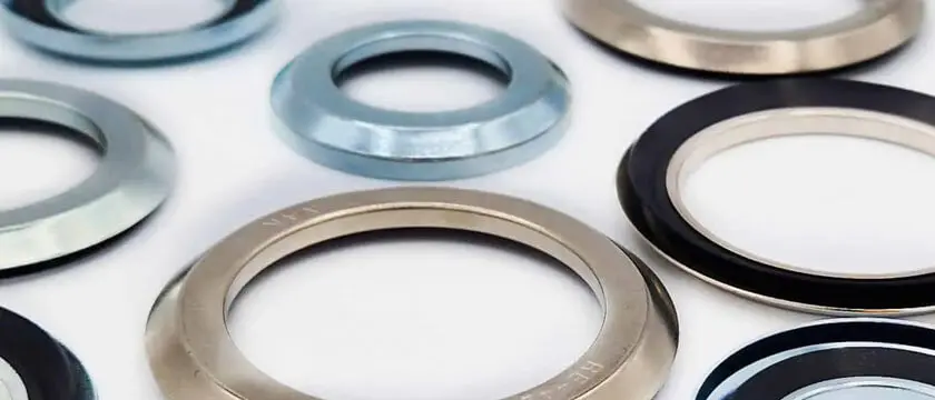 NBR, Viton FKM, and PTFE spring-energized seals arranged by size class on a CNC-machined metal surface
